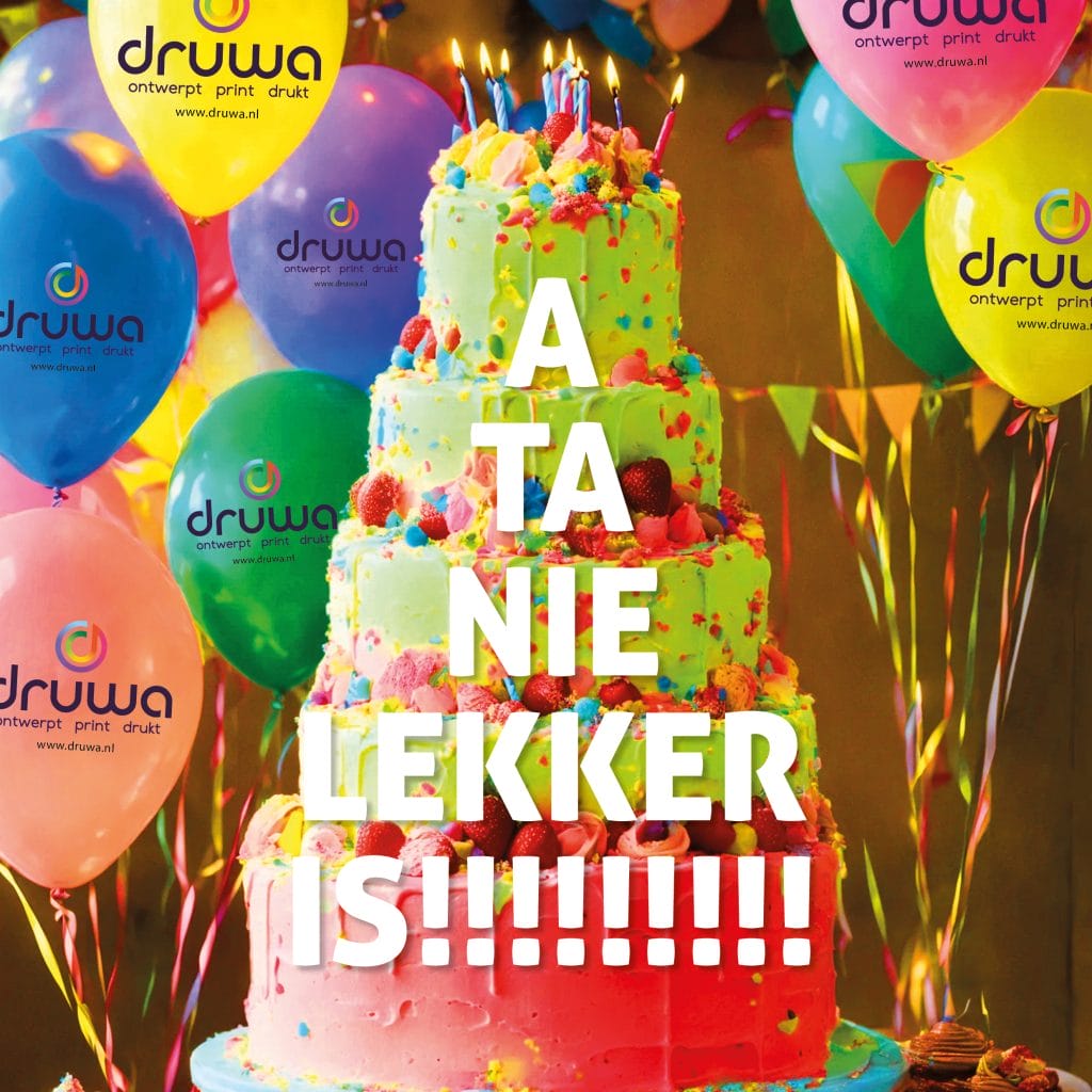 carnaval-2026 Een grote taart met laagjes en botercrime versierd met aardbeien met de tekst erover "A ta nie lekker is". Daarachter ballonnen bedrukt met het logo Druwa. Voor carnaval 2026 in Hulst